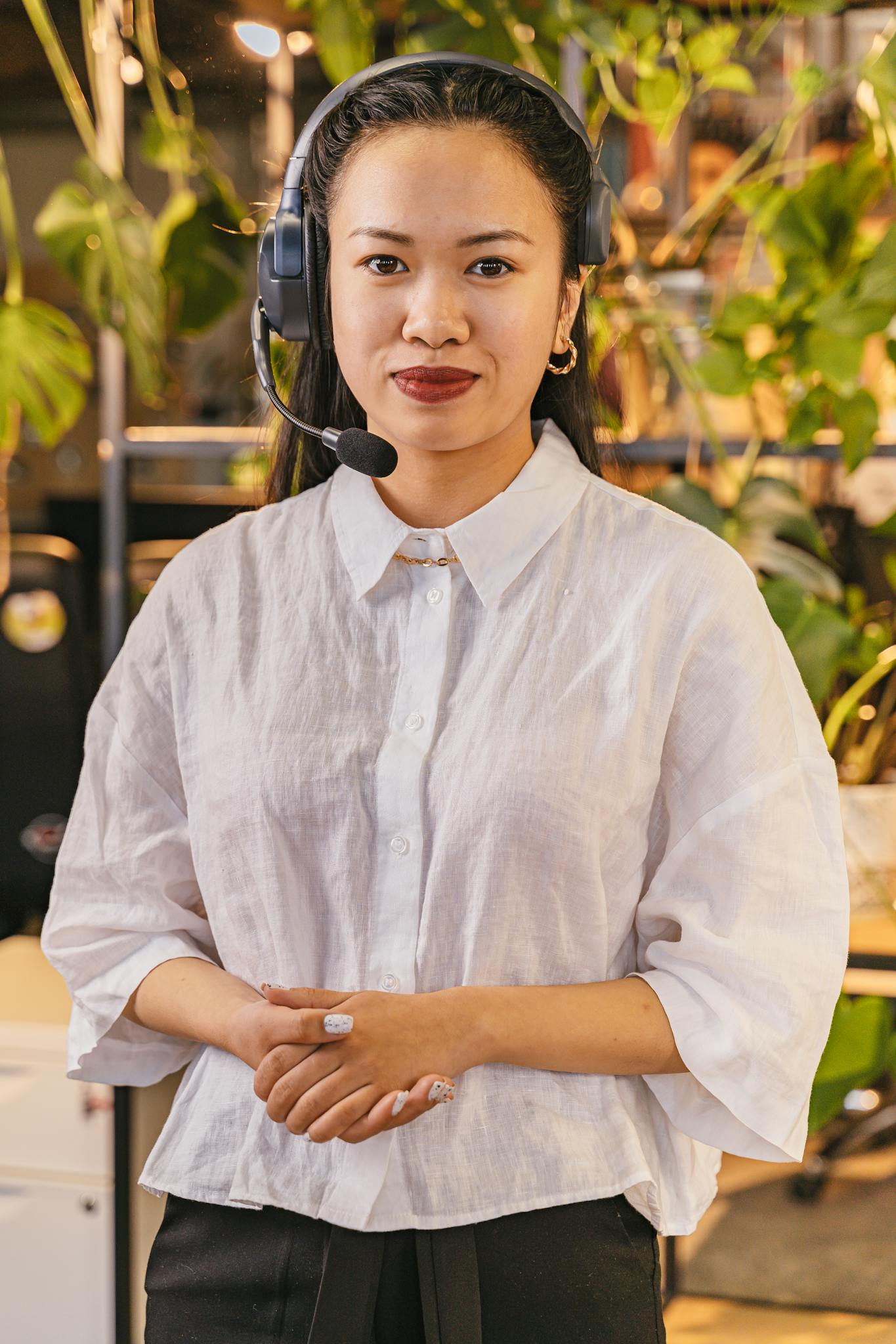 Smiling businesswoman with headset providing customer support in a modern office setting.